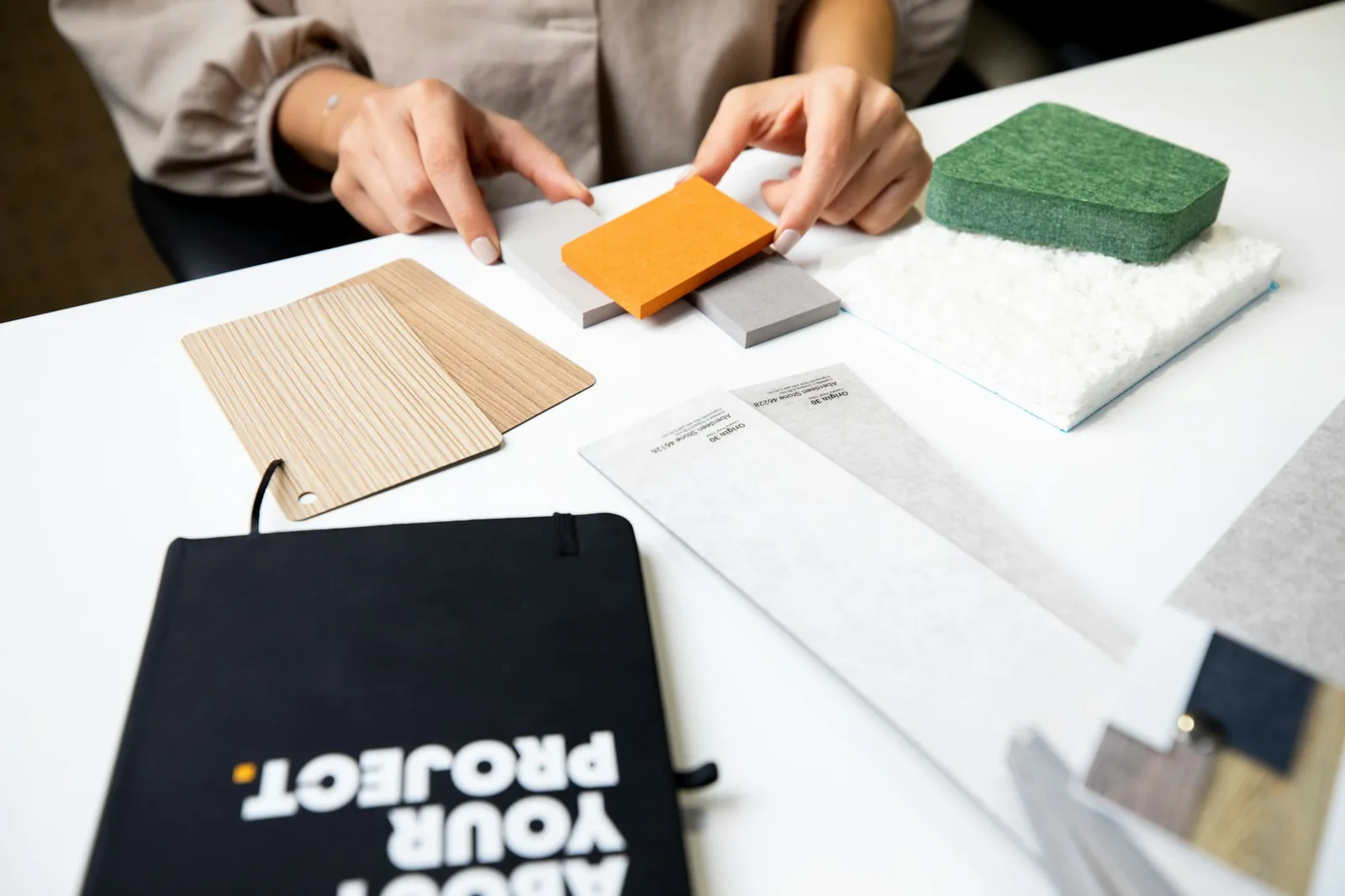 Material samples, timber veneers and paint chips laid out on a table during a consultation.
