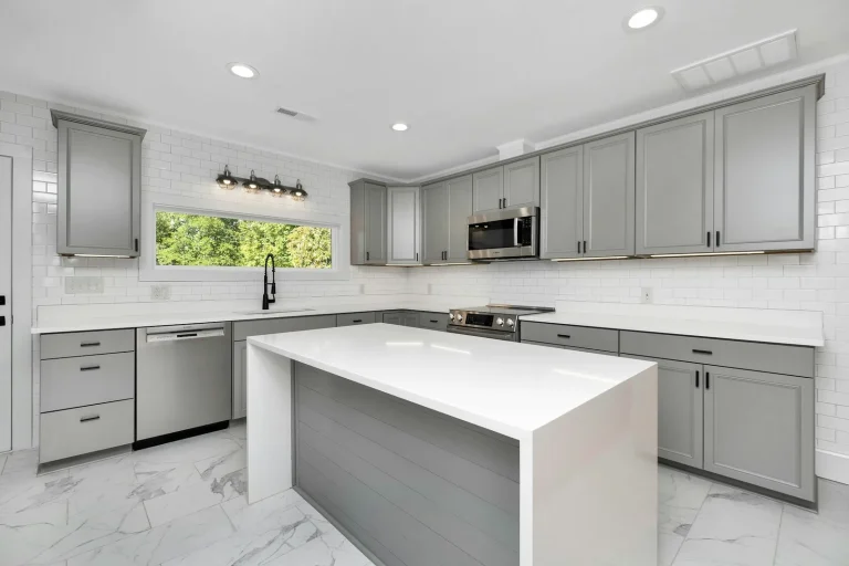 A grey shaker kitchen with a marble-topped island and tiled splashback.