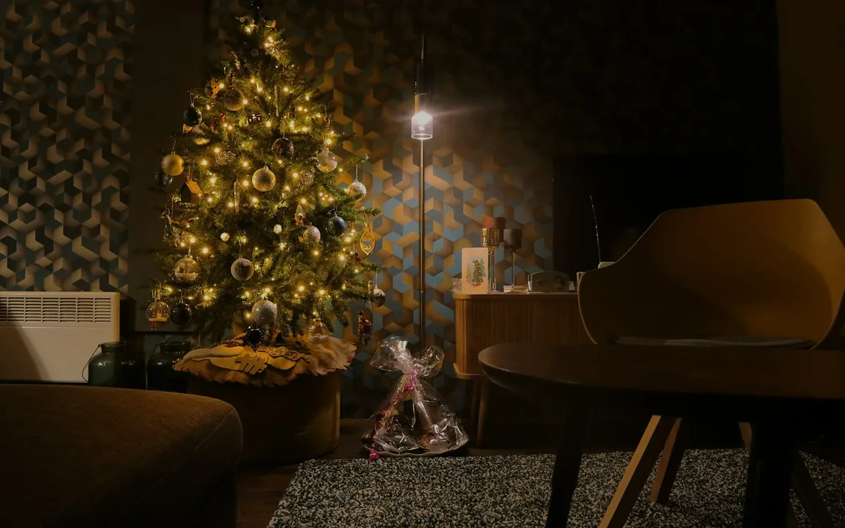 A living room dressed for the season, lit tree beside the seating.