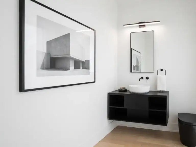 Large contemporary powder room with white walls, a large framed black and white architectural photograph on the side wall and a black floating vanity
