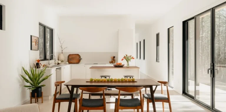 Dining room styled for a listing: a long timber table, upholstered chairs and a clear sightline to the windows.