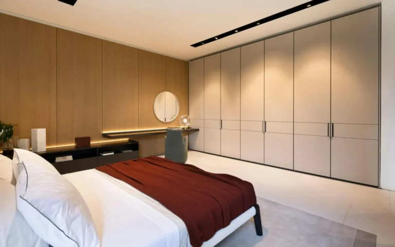 A bedroom with a full run of assembled wardrobes and a dressing table.