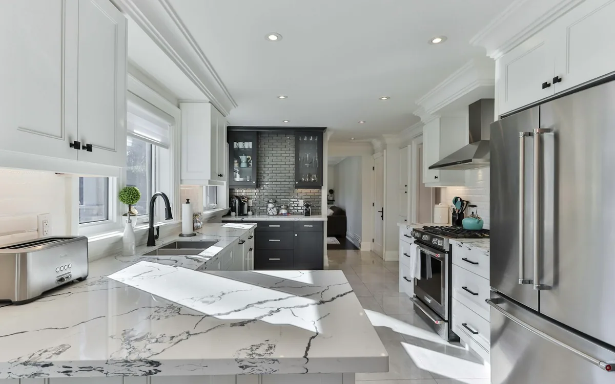 A bright kitchen with a veined marble island and pale cabinetry.