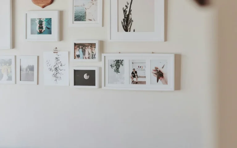 A gallery wall of small framed prints arranged across a pale wall.