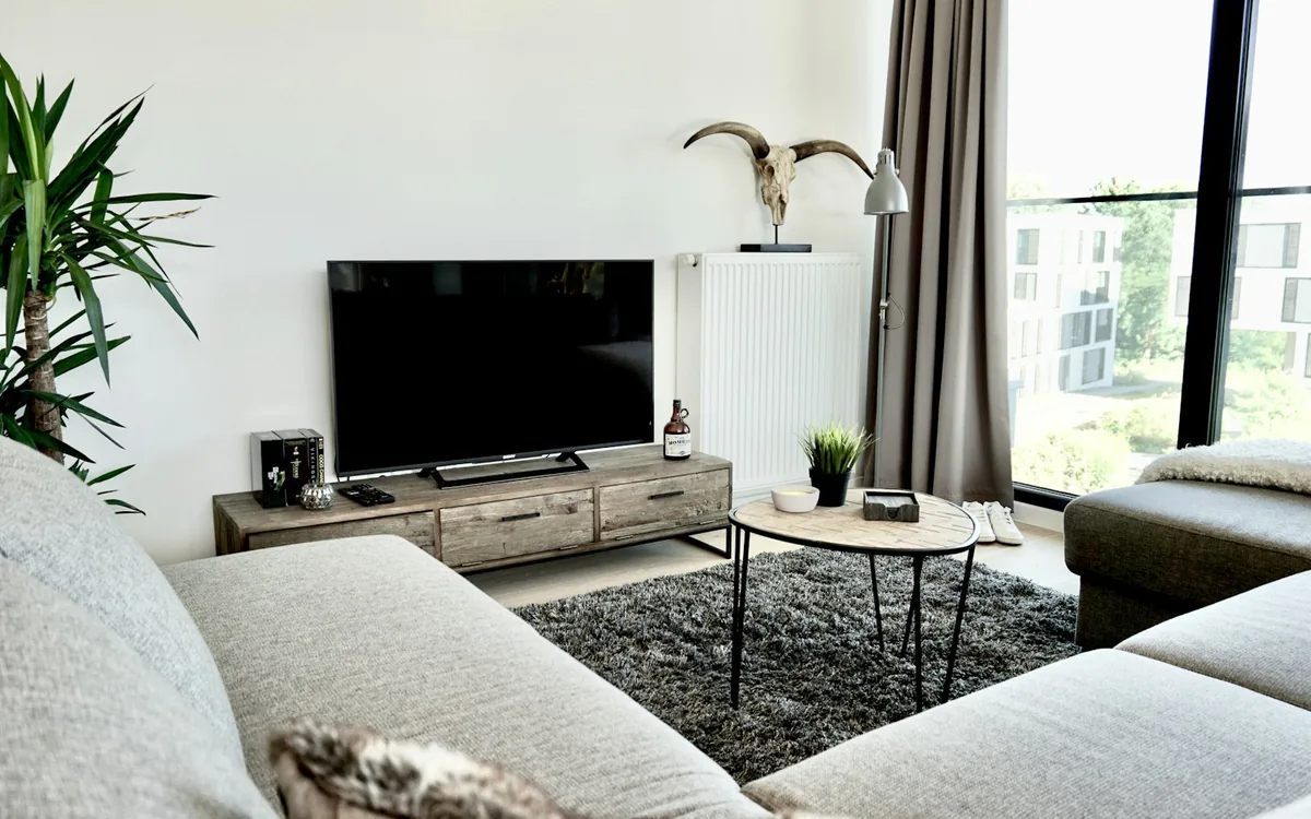 A television set above a low timber console, at seated eye level in a neutral living room.