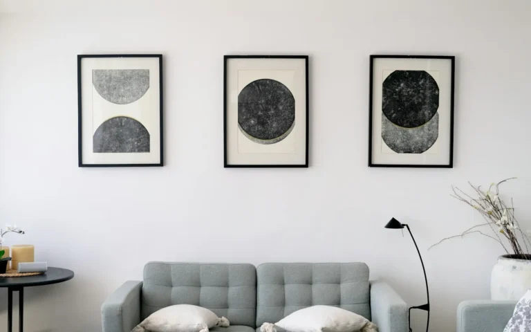 Three framed prints hung as a set above a pale sofa.