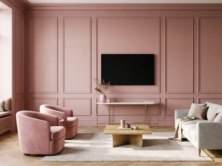 Large modern living room with a dusty rose wall of picture frame molding, a switched-off TV centered in one panel above a marble-top console and two pink velvet chairs