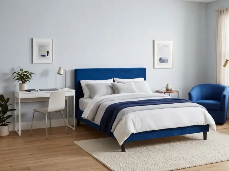 Medium modern bedroom with a cobalt velvet bed on a pale blue wall, a slim desk used as one nightstand, a cobalt reading chair in the corner and a floor lamp
